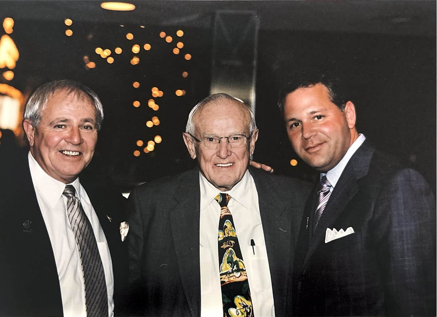 Dave Barrick and Stephen Crystal standing either side of an older gentleman at an evening event.