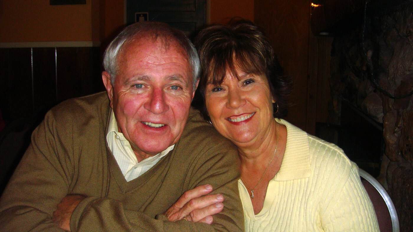 Dave Barrick seated closely with a family member, both smiling towards the camera.